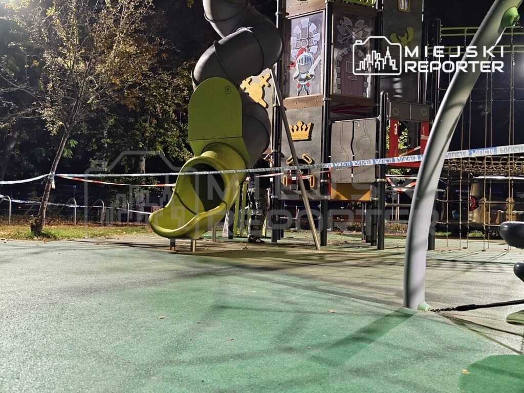 Zabezpieczony taśmą plac zabaw z zieloną zjeżdżalnią i wielopoziomową konstrukcją do zabawy nocą