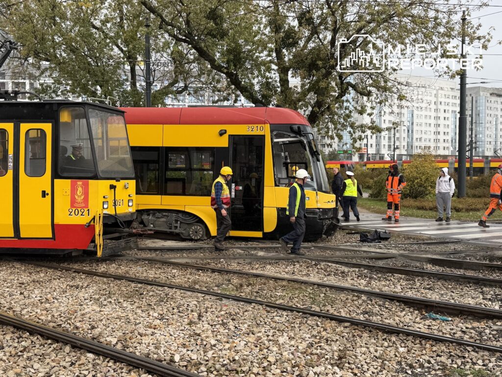 Dwa żółto-czerwone tramwaje stoją na torach, a pracownicy w kamizelkach odblaskowych oglądają uszkodzony skład.
