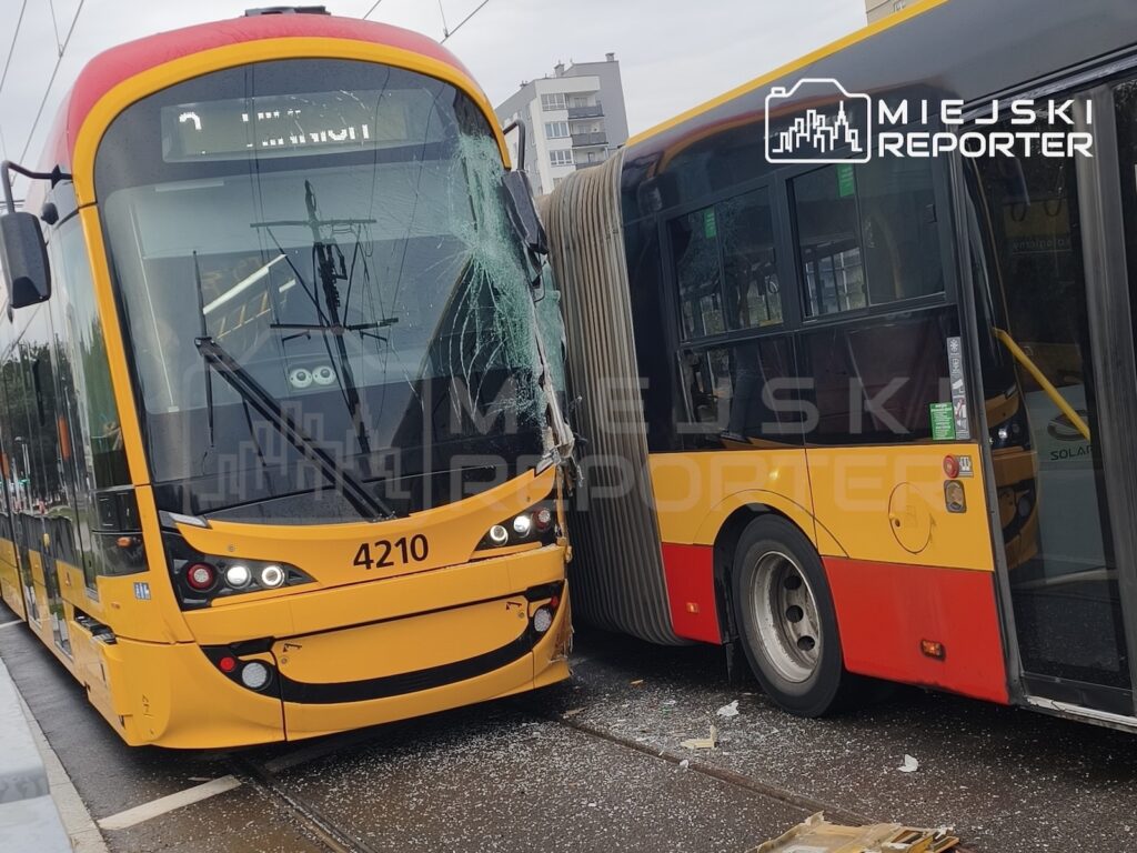 Uszkodzony żółty tramwaj i czerwono-żółty autobus stoją zderzone na torowisku miejskim.