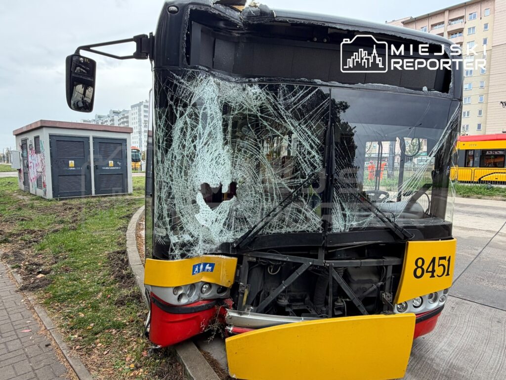 Tramwaj z rozbitą przednią szybą i uszkodzonym zderzakiem stoi przy torowisku, obok bloku mieszkalnego.