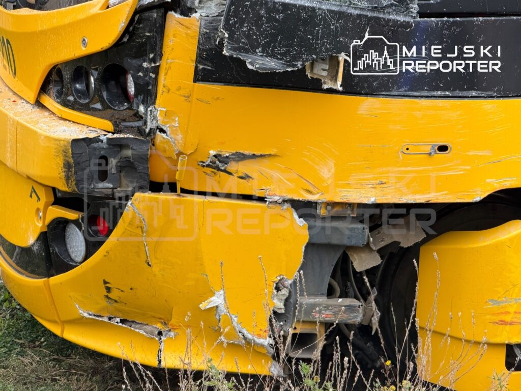Zbliżenie na mocno uszkodzony żółty pojazd z rozbitą karoserią i odsłoniętymi elementami mechanicznymi.