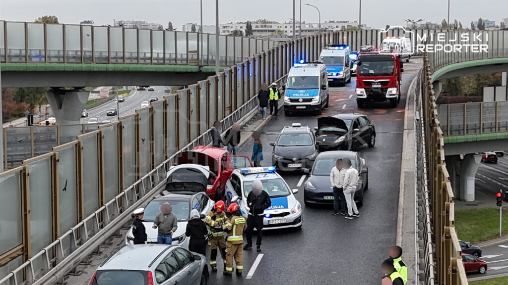 Rozbite samochody, policyjne radiowozy i strażacy na drodze pod wiaduktem po karambolu wielopojazdowym