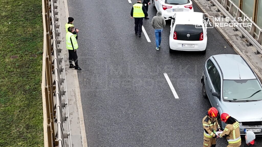 Policjanci i strażacy na drodze przy kilku samochodach uczestniczących w karambolu na moście