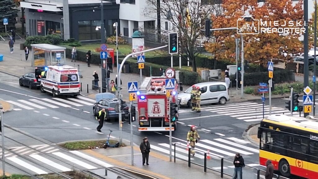 Dwie karetki i wóz strażacki stoją na skrzyżowaniu przy przejściu dla pieszych, obok pracują służby ratunkowe.