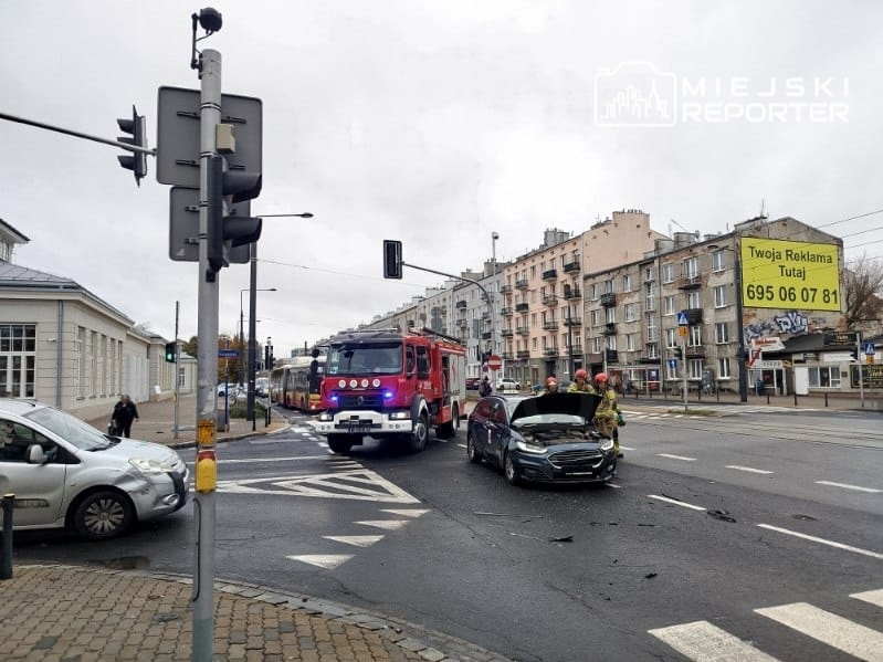 Wóz strażacki i samochód osobowy stoją po kolizji na miejskim skrzyżowaniu.