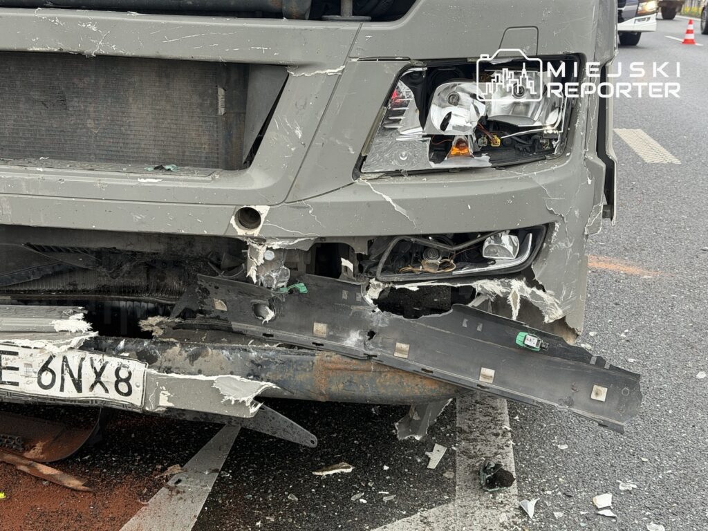 Uszkodzony przód ciężarówki z rozbitą lampą i oderwanym zderzakiem na jezdni.