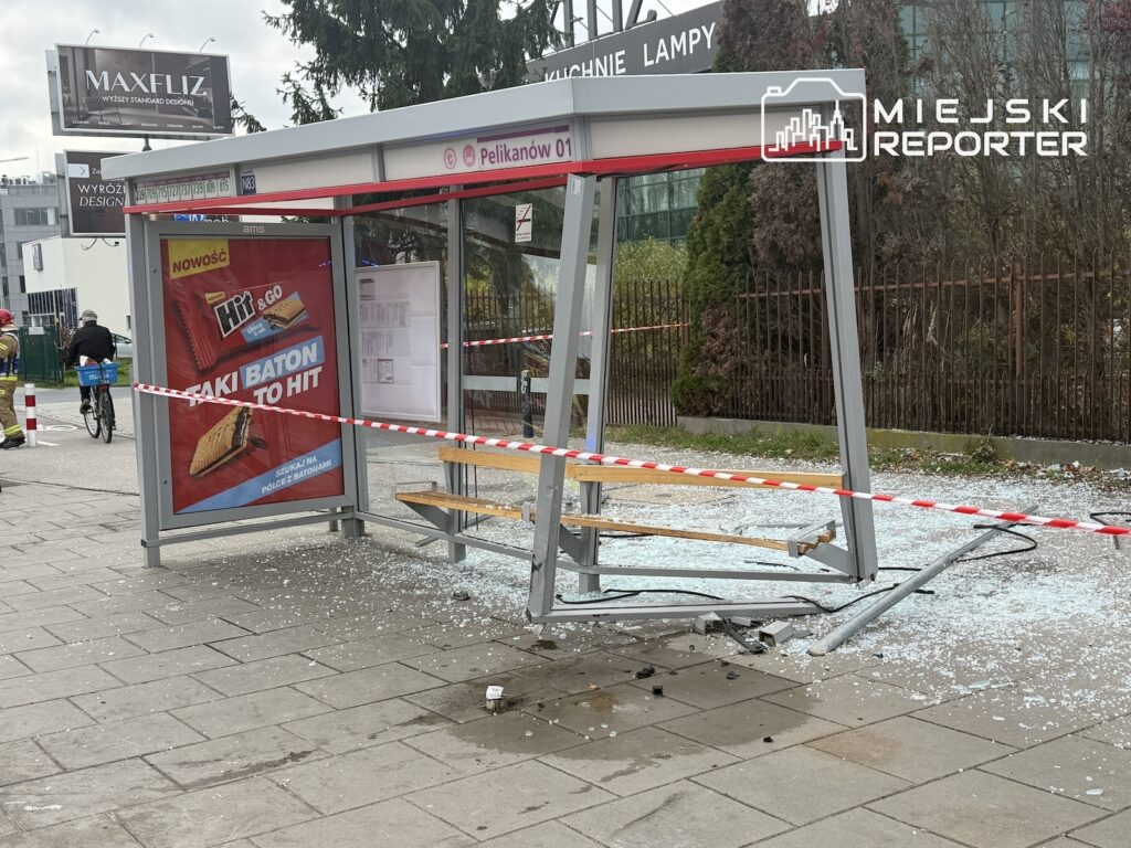 Uszkodzona wiata przystanku Pelikanów 01, otoczona taśmą, ze szkłem rozsypanym na chodniku.