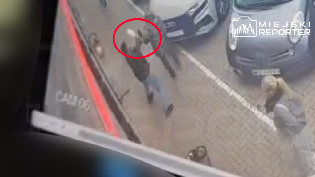 Nagranie z monitoringu pokazuje osoby na chodniku między zaparkowanymi samochodami; jedna z nich jest zaznaczona czerwonym